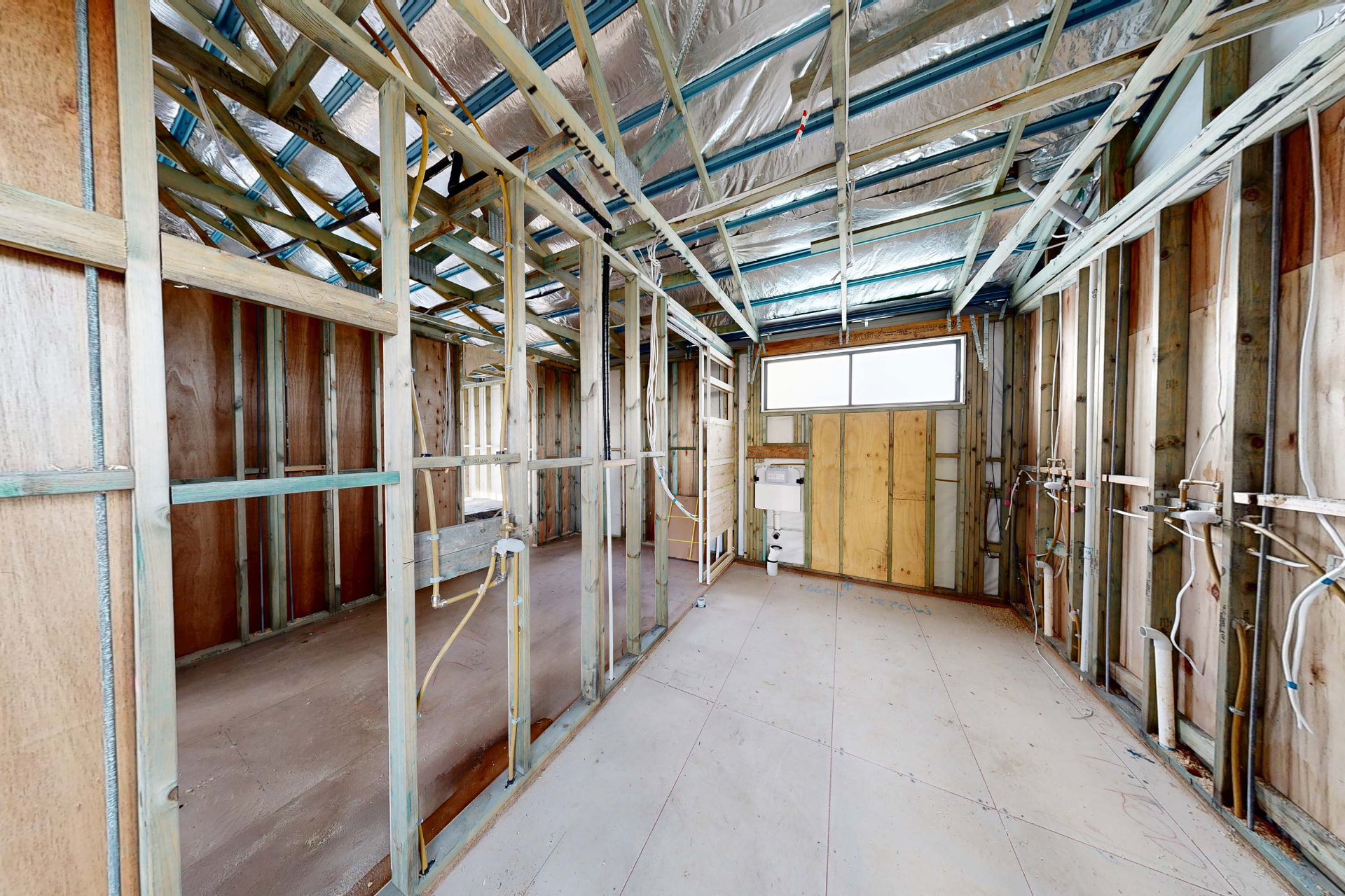 Interior of a pre-plaster residential construction site with exposed framing and services